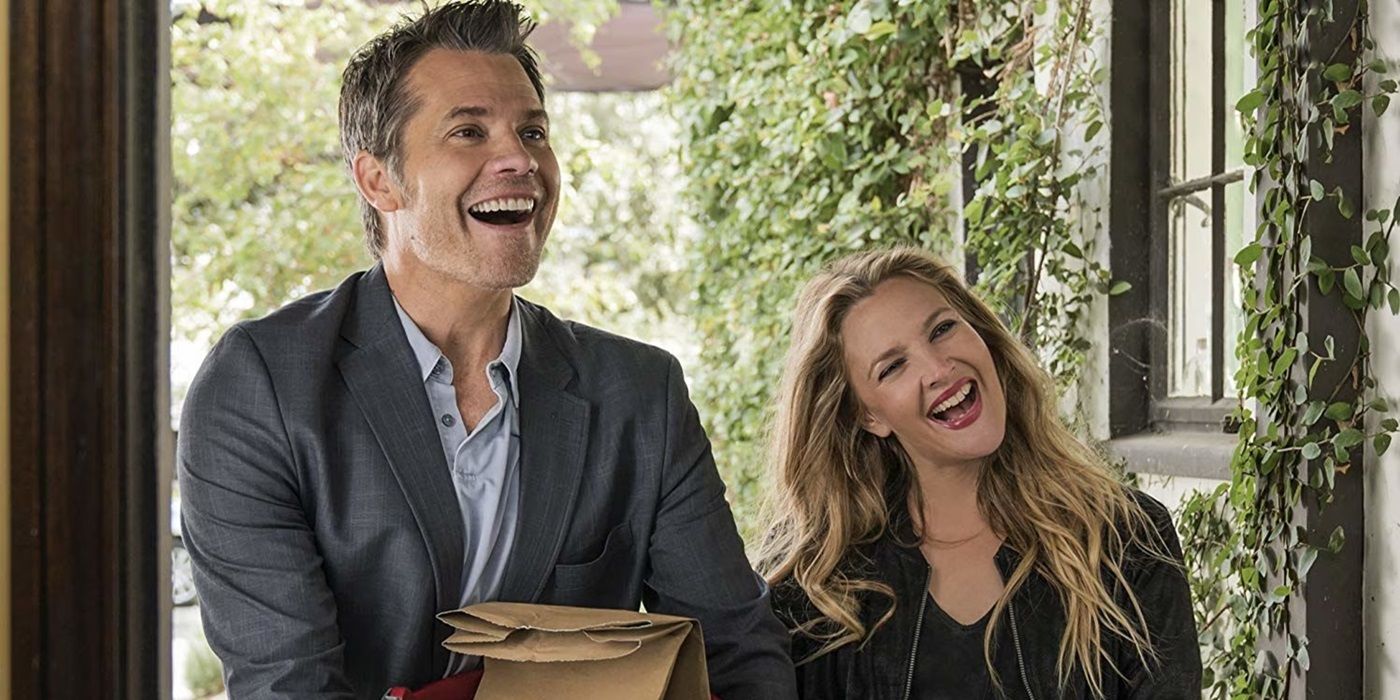 Joel (Timothy Olyphant) & Sheila (Drew Barrymore) standing in a neighbor's doorway smiling in Santa Clarita diet