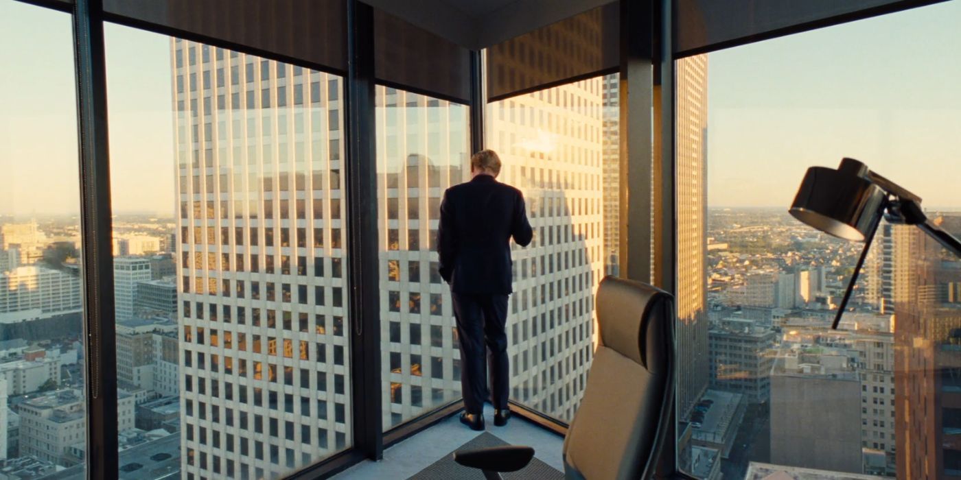 Jesse Plemons with his back turned, staring out a skyscraper window in Kinds of Kindness.