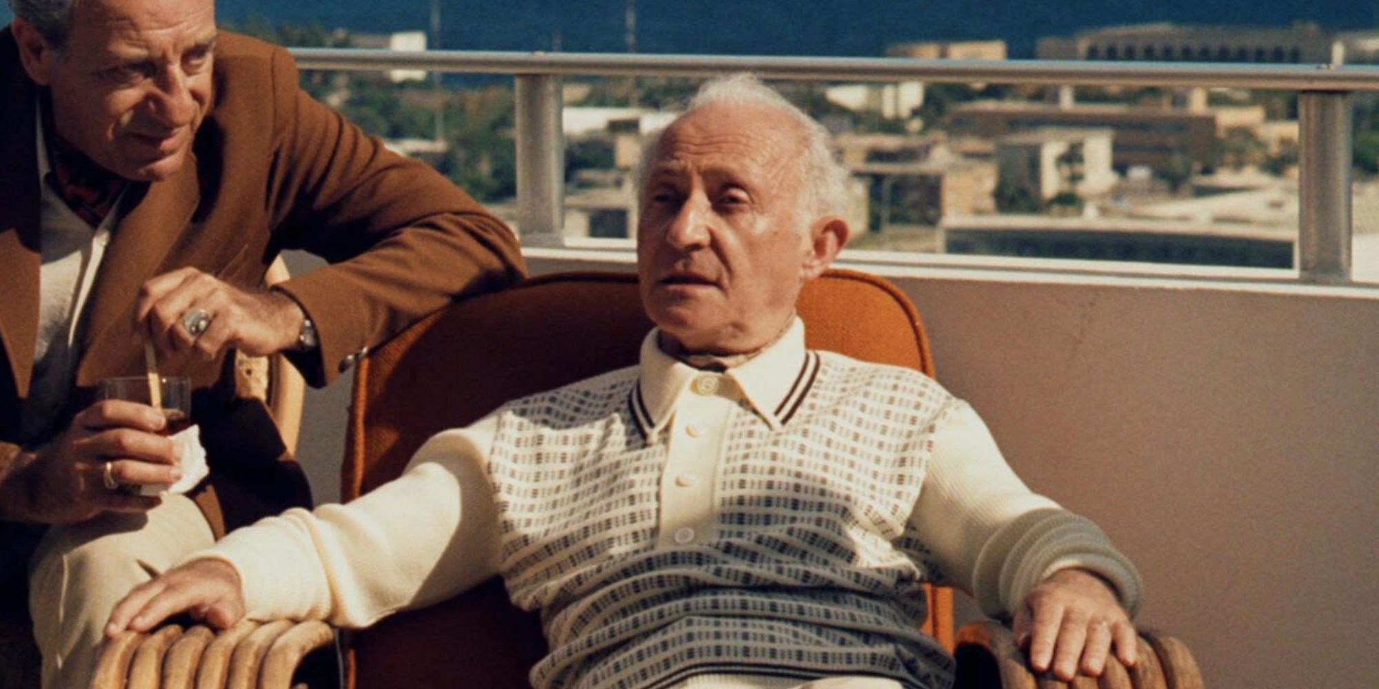 Lee Strasberg sitting in a chair in The Godfather: Part II (1974)