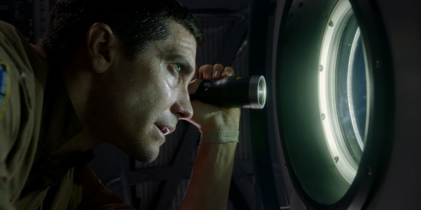 Jake Gyllenhal stares out the window with a flashlight