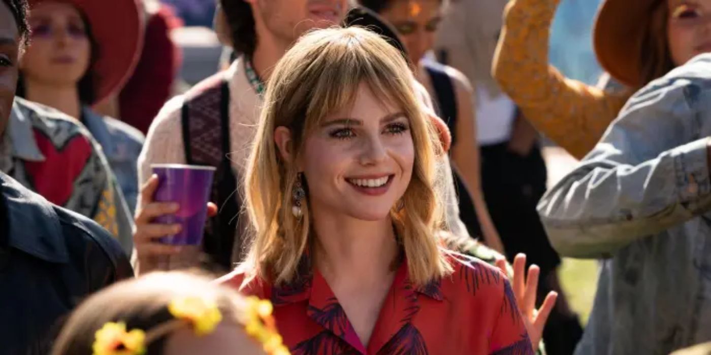 Lucy Boynton smiling in the middle of a crowd in a scene from 'The Greatest Hits'