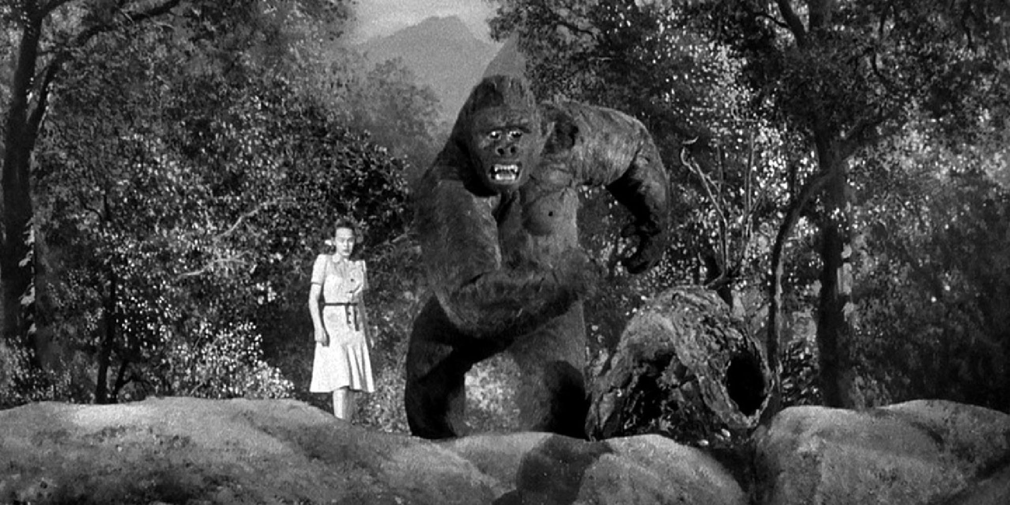 A woman stands next to a giant gorilla in a forest in Mighty Joe Young 1949.