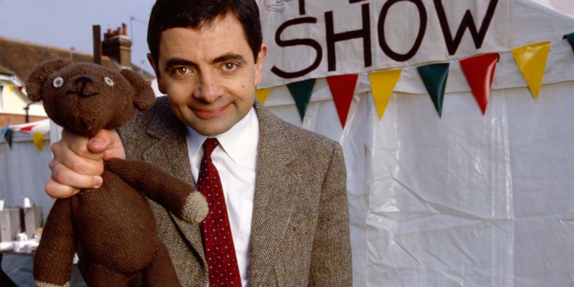 Mr. Bean from Mr. Bean standing holding his teddy bear