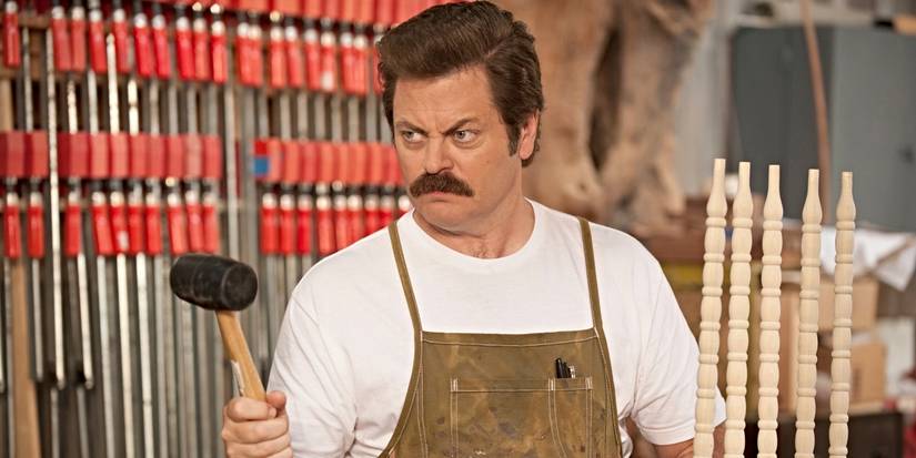 Nick Offerman as Ron Swanson, holding a hammer and wearing an apron in Parks and Recreation