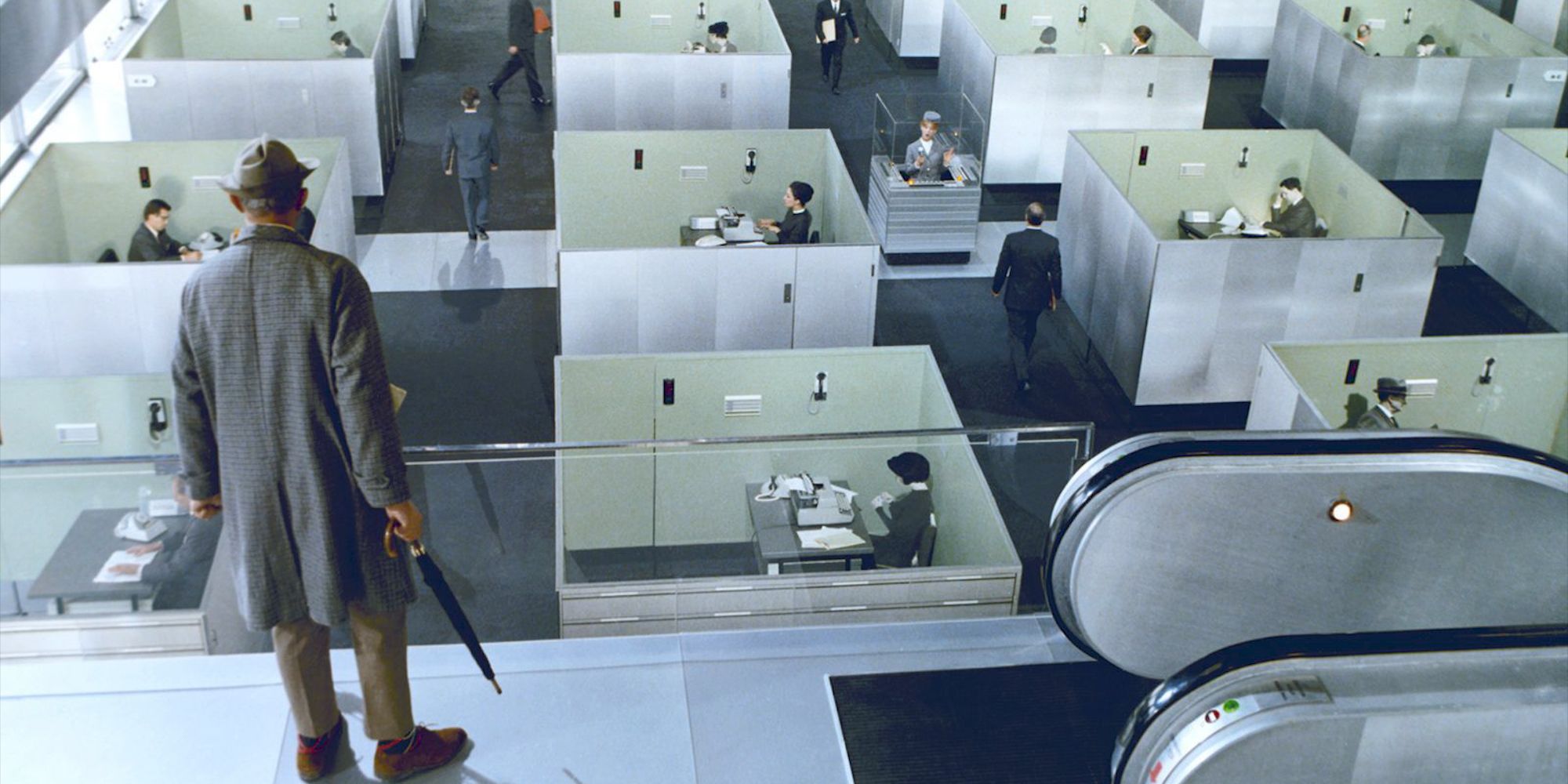 A man looking at people working in cubicles.