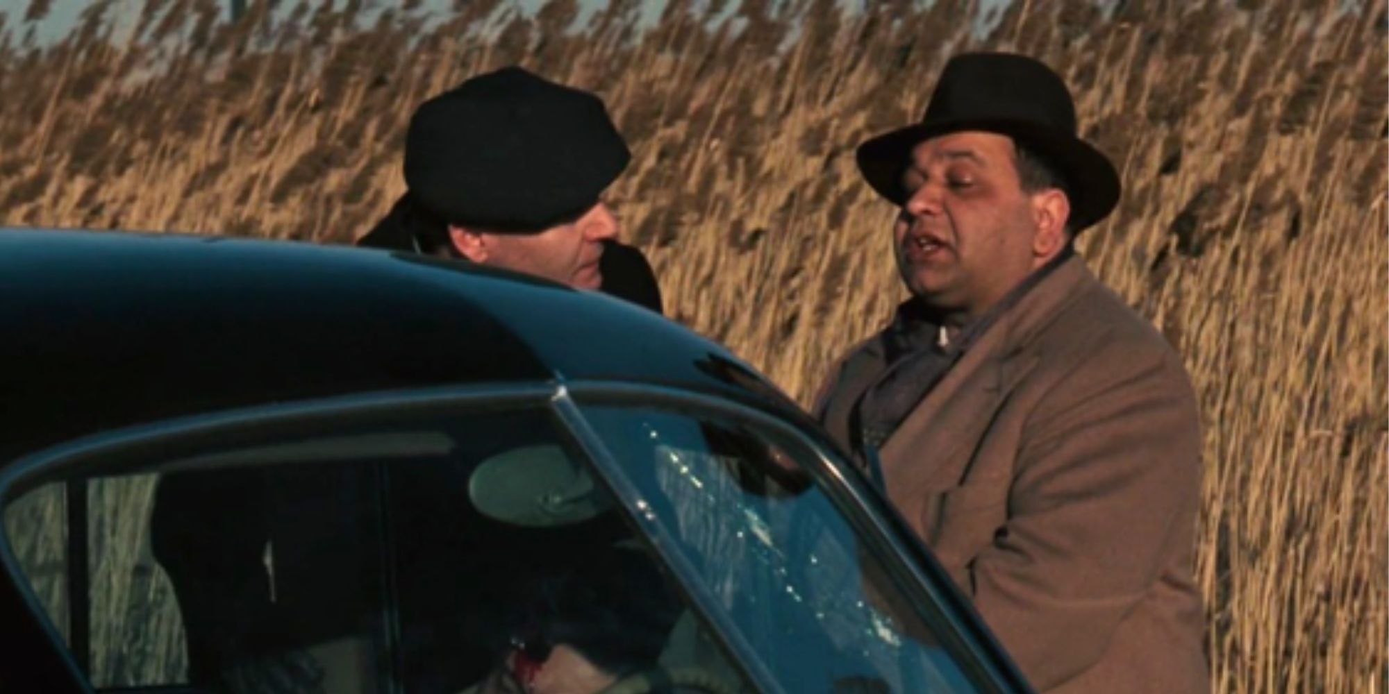 Richard Castellano talking to someone in front of a car next to a cornfield in The Godfather (1972)