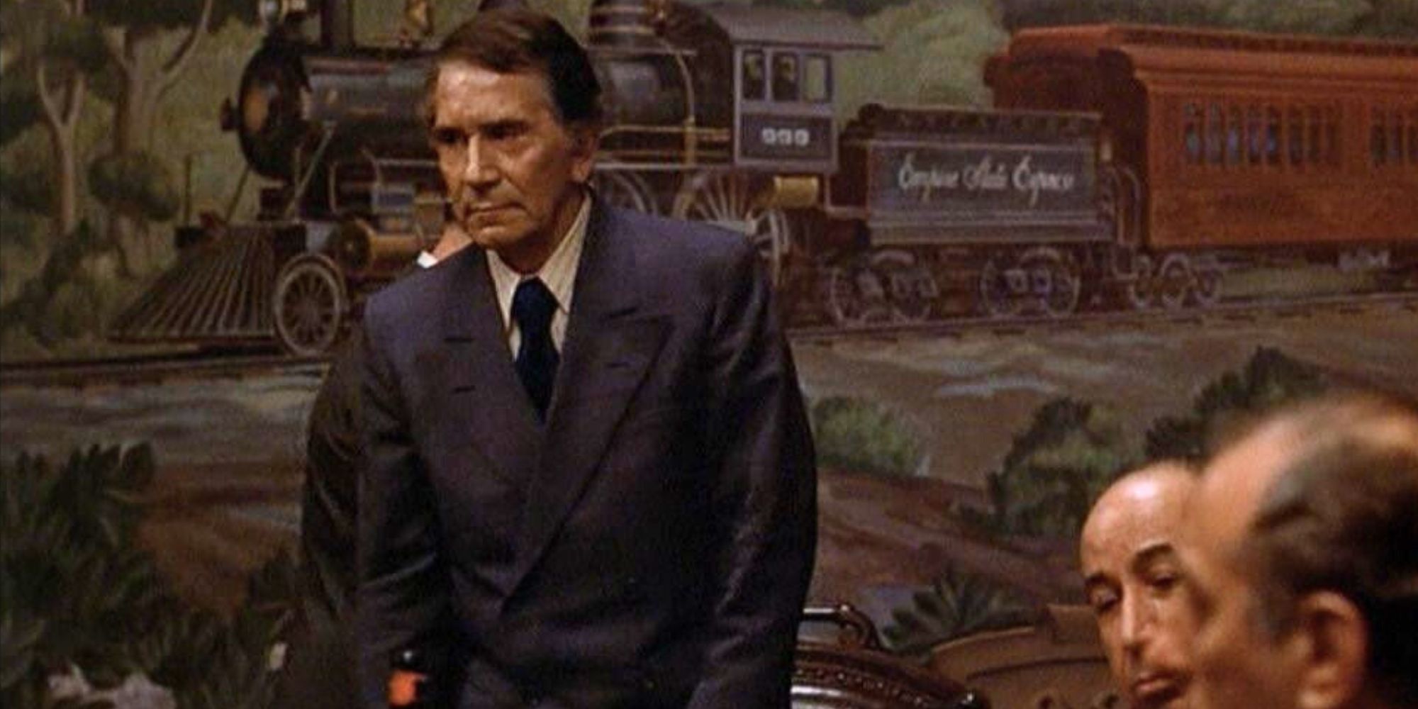 Richard Conte standing up in front of a table in The Godfather (1972)