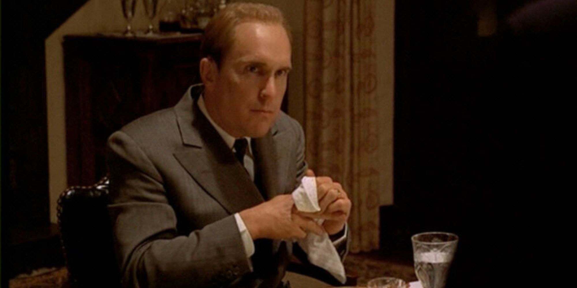 Robert Duvall sitting at a dinner table with a napkin in his hand in The Godfather (1972)