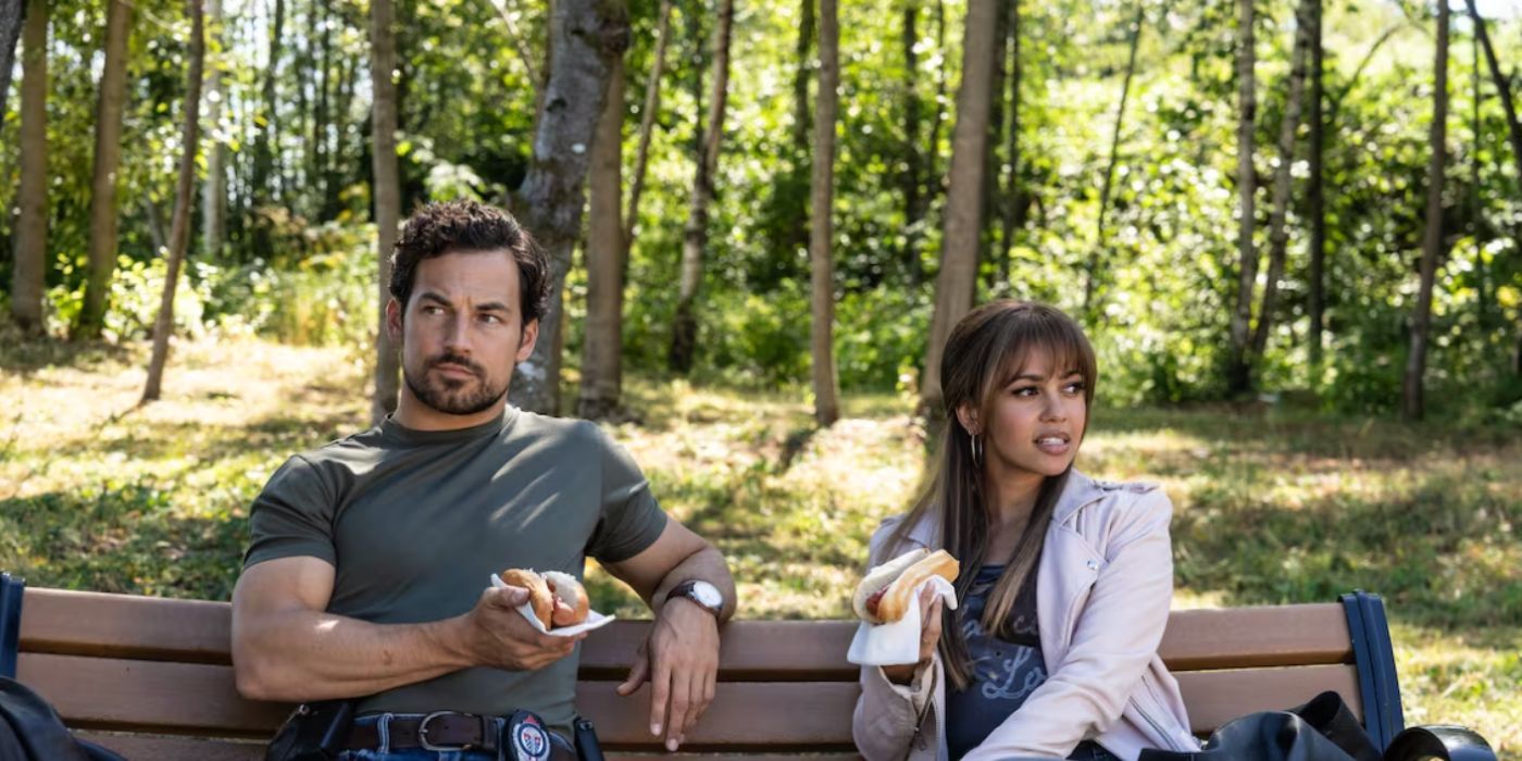 Vanessa Morgan y Giacomo Gianniotti, quienes interpretan a Max y Ellis en Wild Cards, sentados en un banco del parque.