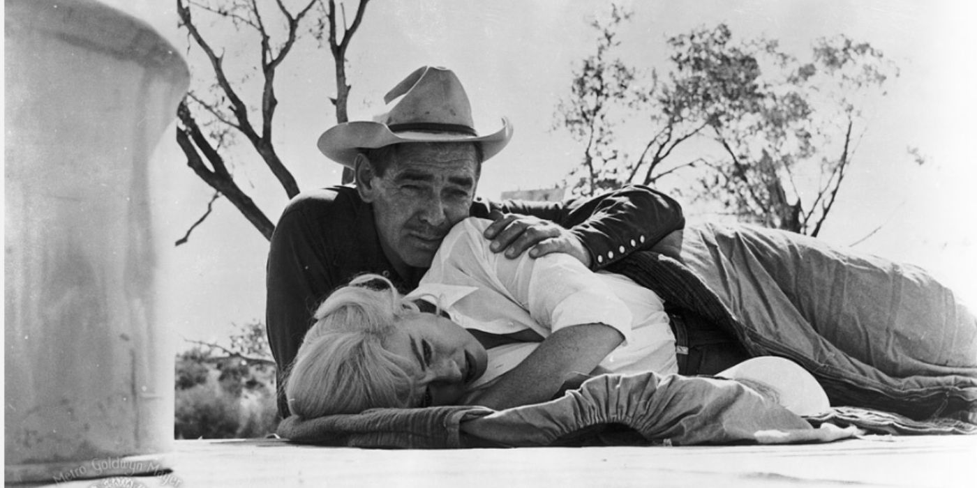 Clark Gable and Marilyn Monroe as Gaylord wearing a cowboy hat and Roslyn laying down on the ground in 'The Misfits'