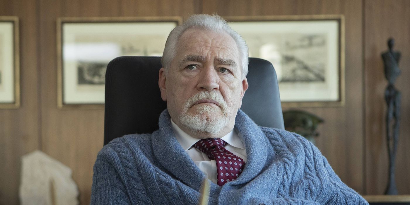 Logan sitting in his chair with an angry face wearing a sweater vest in a scene from Succession.