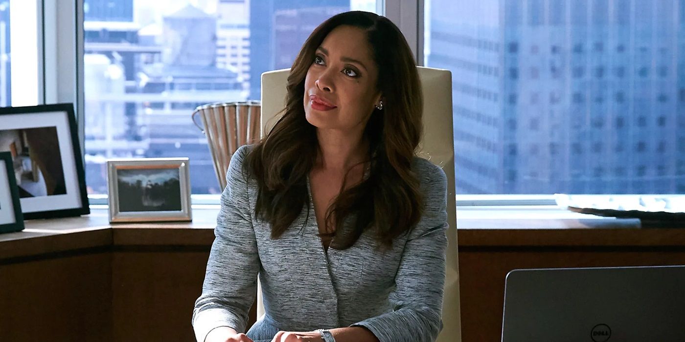Gina Torres as Jessica Pearson sitting at her desk look up at someone in Suits