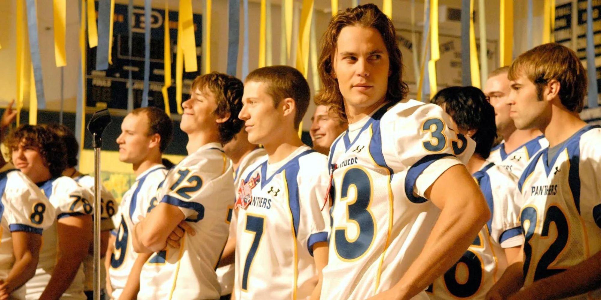 Taylor Kitsch as Tim Riggins and Zach Gilford as Matt Saracen wearing football jerseys in Friday Night Lights.