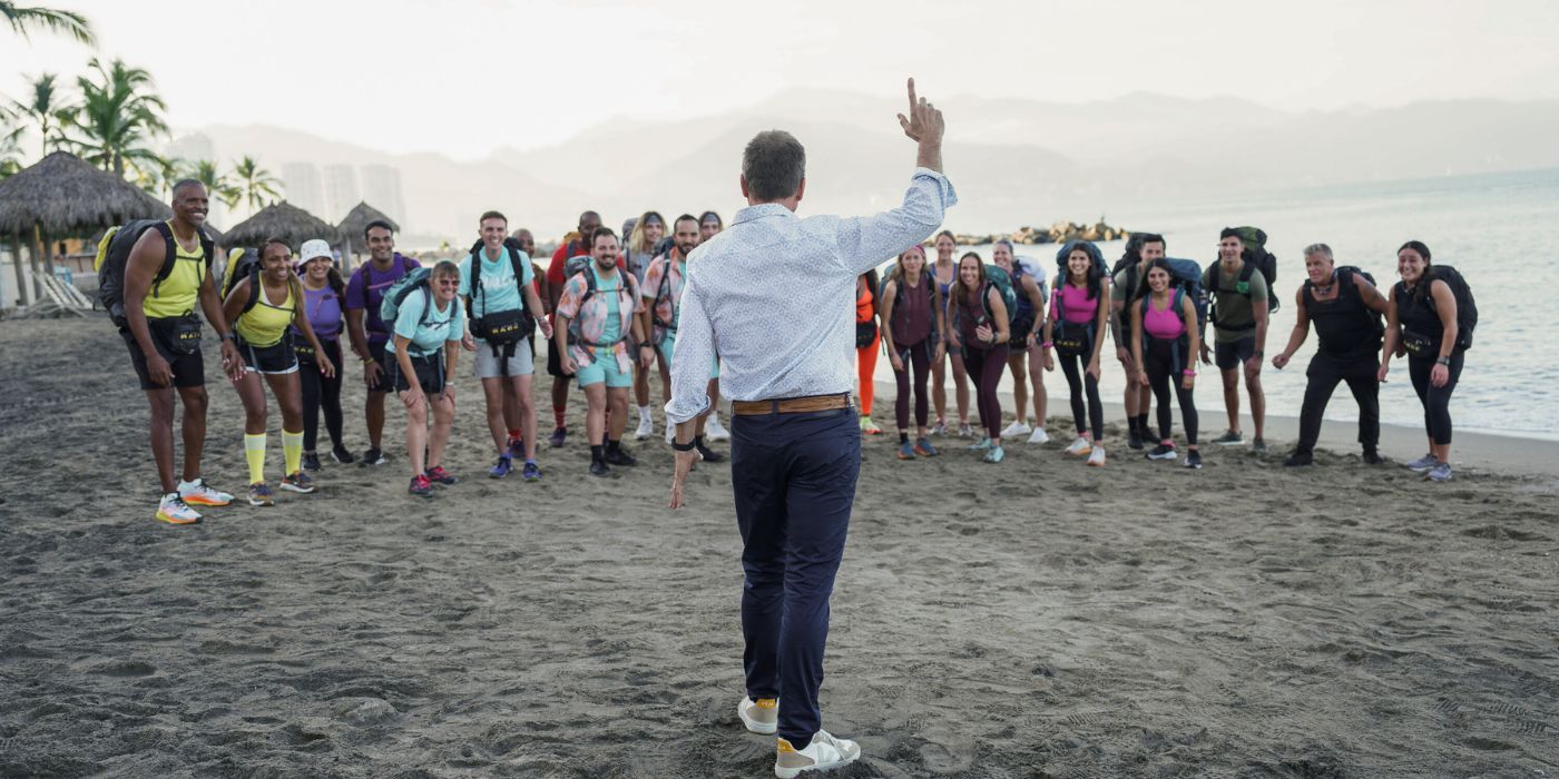 Phil Keoghan, pointing a finger gun in the air in front of the contestants of The Amazing Race Season 36.