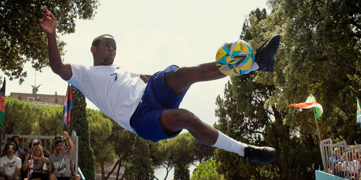 Michael Ward as Vinny, in the air, kicking a soccer ball, in The Beautiful Game.