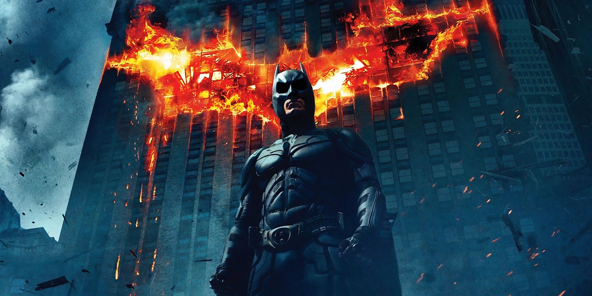 Batman standing in front of a flaming building in The Dark Knight