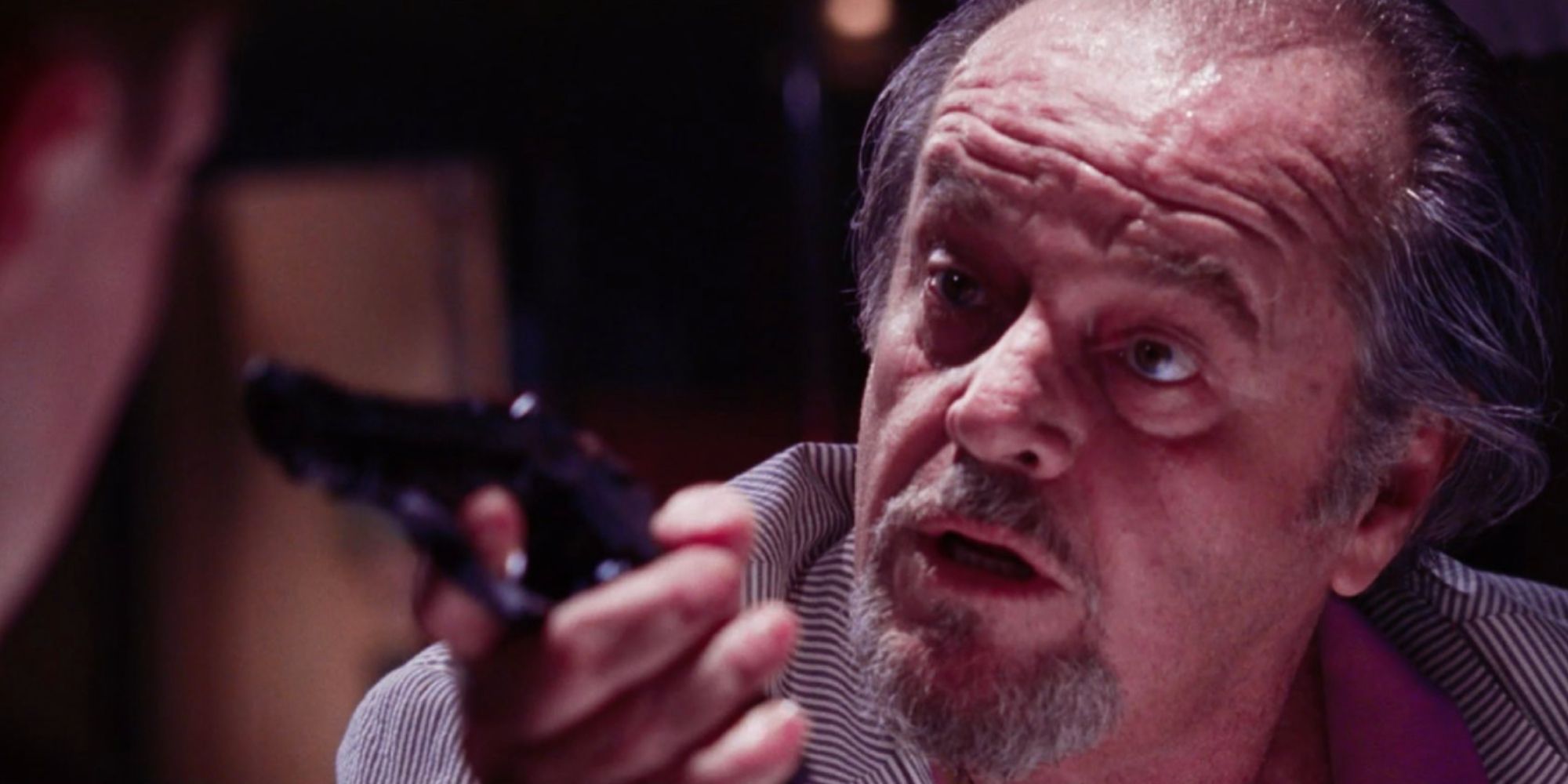 Jack Nicholson as Frank Costello pointing his gun at a person offscreen in The Departed
