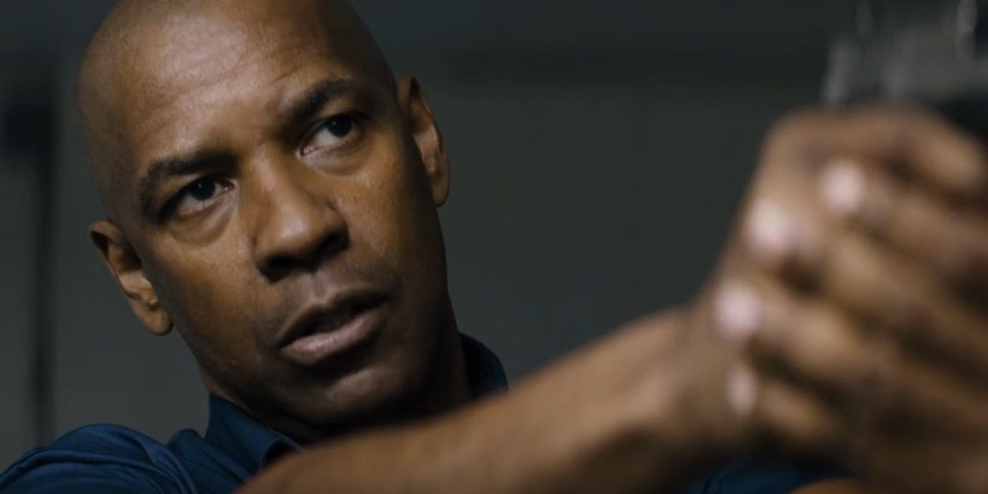Denzel Washington as Robert McCall aiming his gun at a person offscreen in The Equalizer