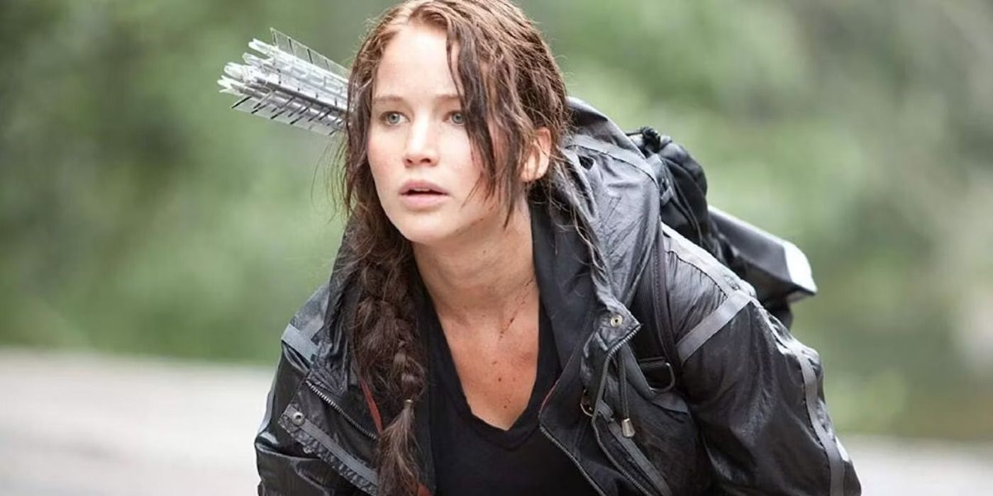 Katniss Everdeen crouching and looking to the distance in The Hunger Games