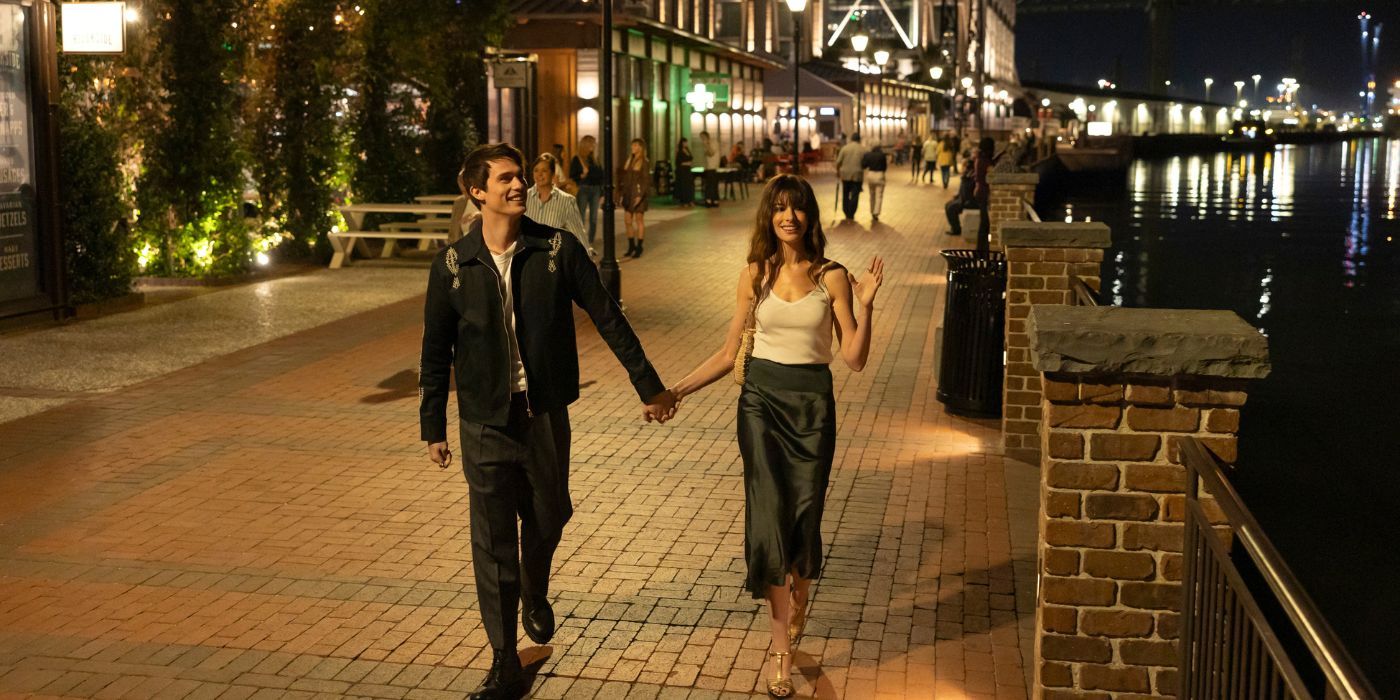 Nicholas Galitzine and Anne Hathaway holding hands while walking down a sidewalk in The Idea of You.