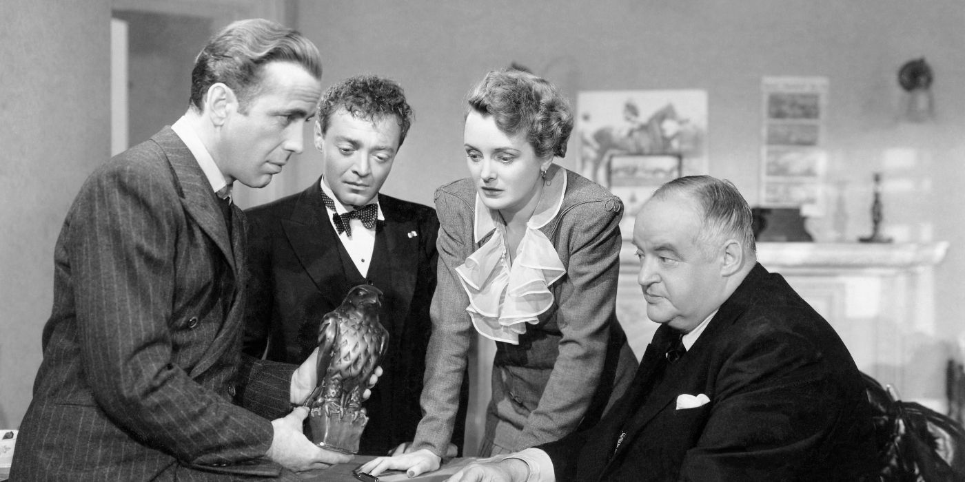 Brigid O'Shaughnessy (Mary Astor), Sam Spade (Humphrey Bogart), and actors Peter Lorre and Sydney Greenstreet all huddled around the Falcon statue in The Maltese Falcon