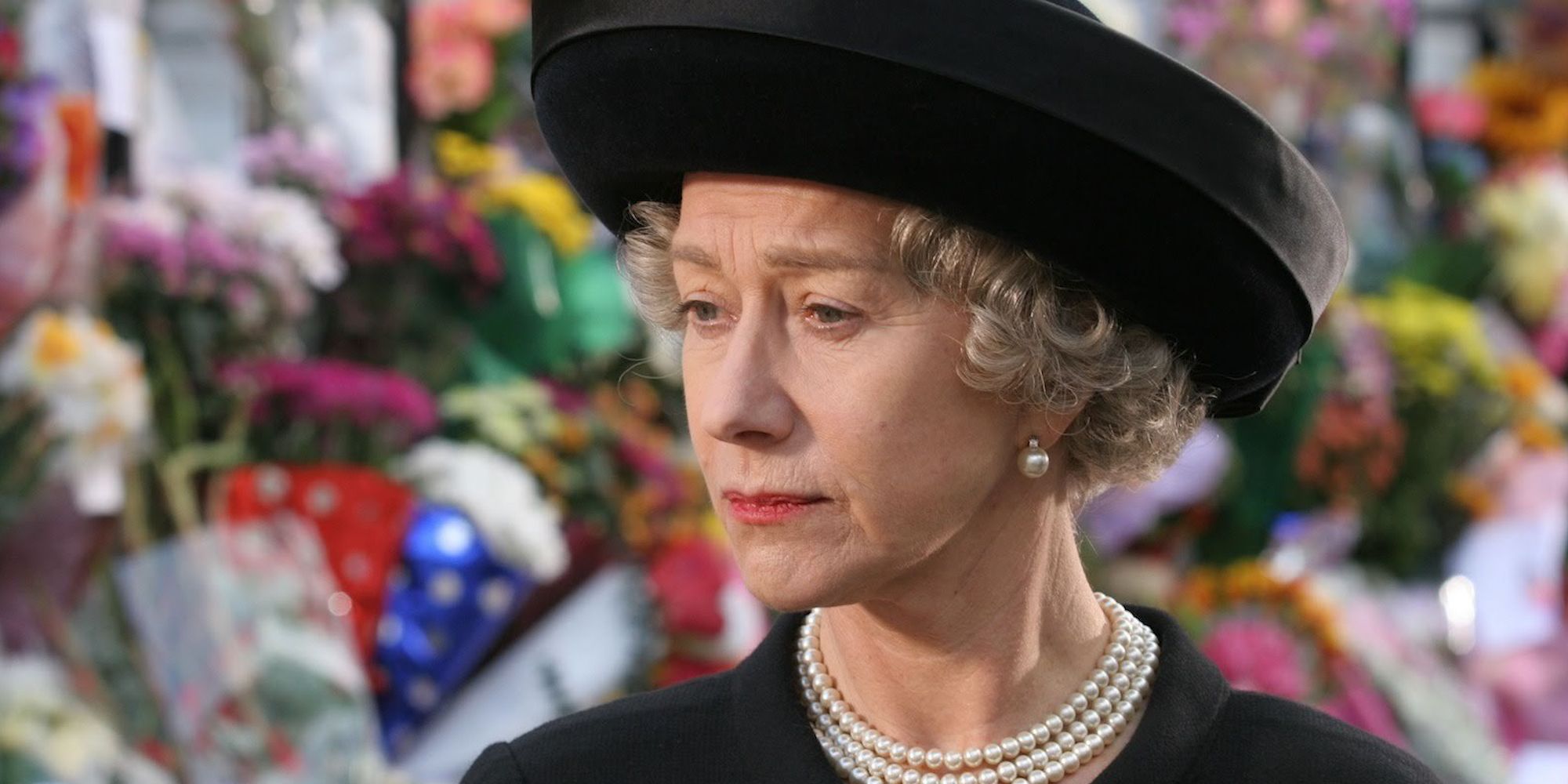 Queen Elizabeth II walking beside a line of pictures of Princess Diana in The Queen