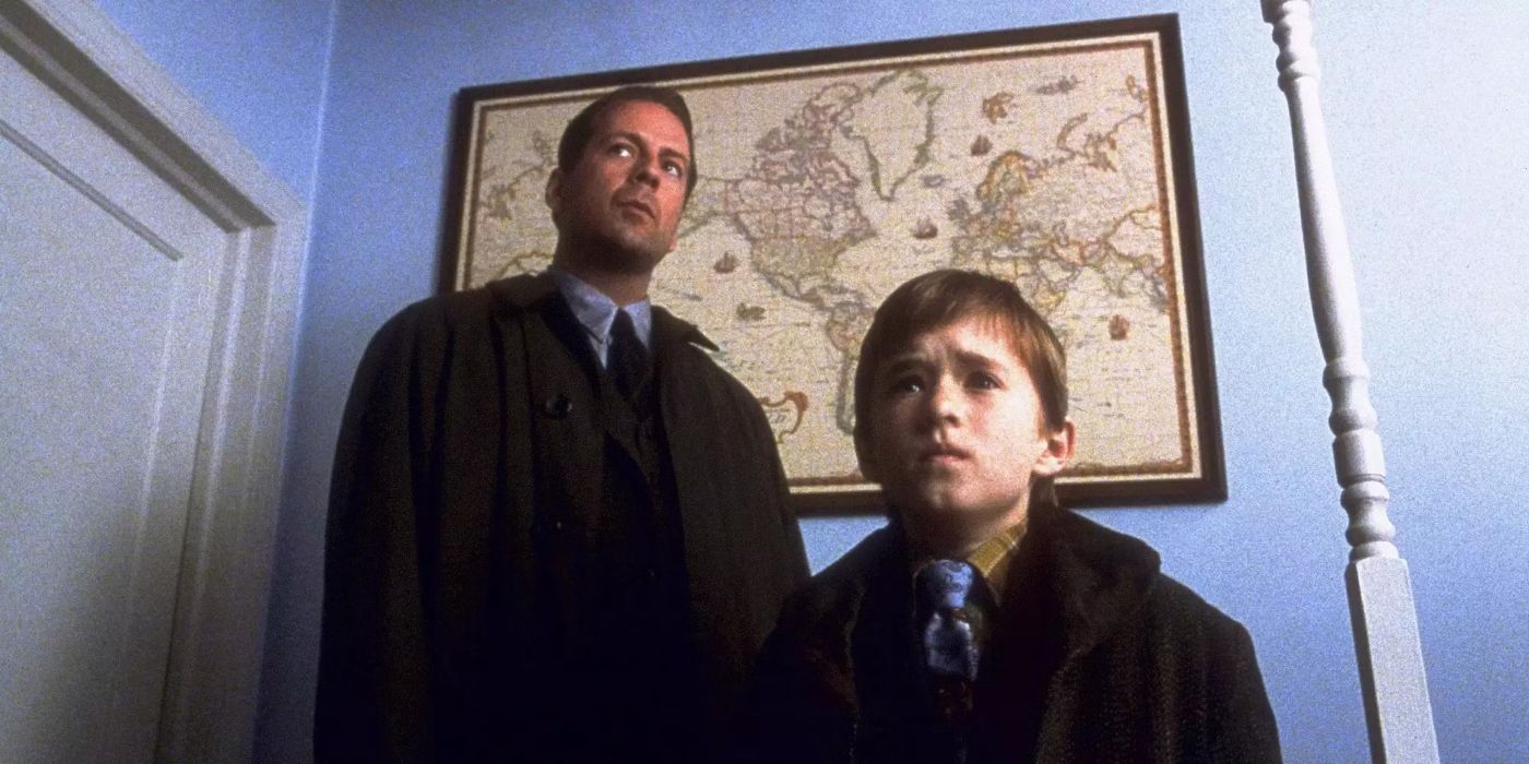 Malcolm (Bruce Willis) and Cole (Haley Joel Osment) looking in the same direction while standing in a room in The Sixth Sense.