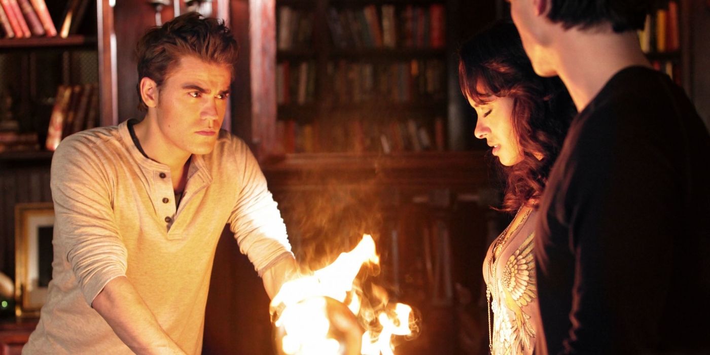 Stefan (Paul Wesley), Bonnie (Kat Graham), and Damon (Ian Somerhalder) standing around a fire in Season 2 of The Vampire Diaries