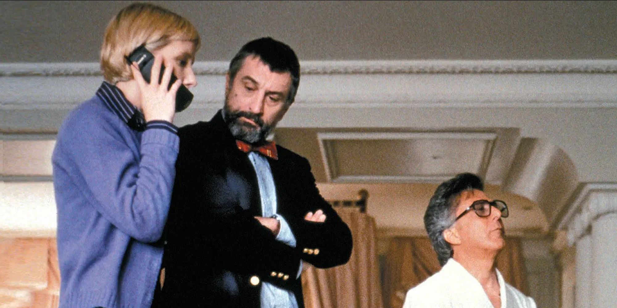 Winnifred on the phone while Conrad and Stanley stand beside her in Wag the Dog