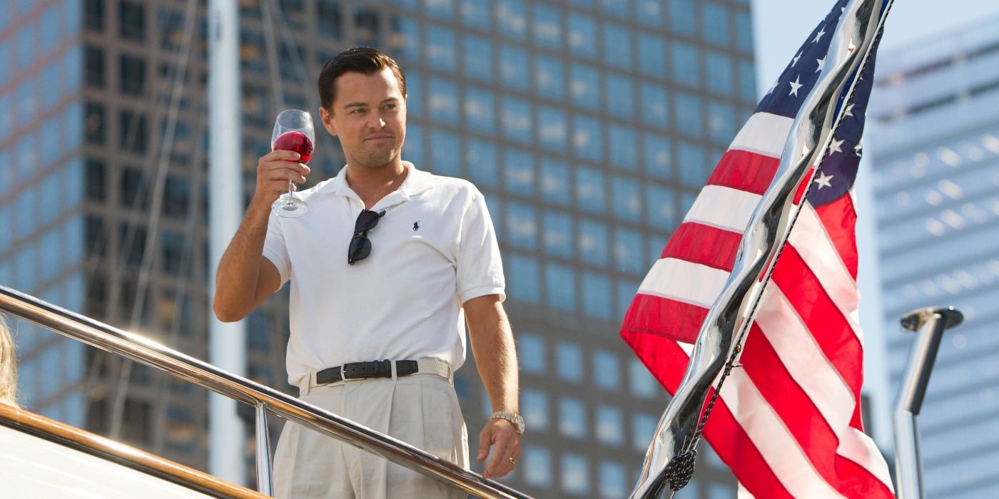 Leonardo DiCaprio as Jordan Belfort, standing on a boat and holding a glass of wine while the American flag waves behind him in The Wolf of Wall Street
