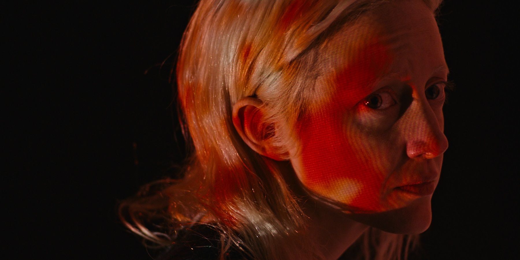 Andrea Riseborough is cast in a creepy, red lighting effect from a projector in 'Possessor'