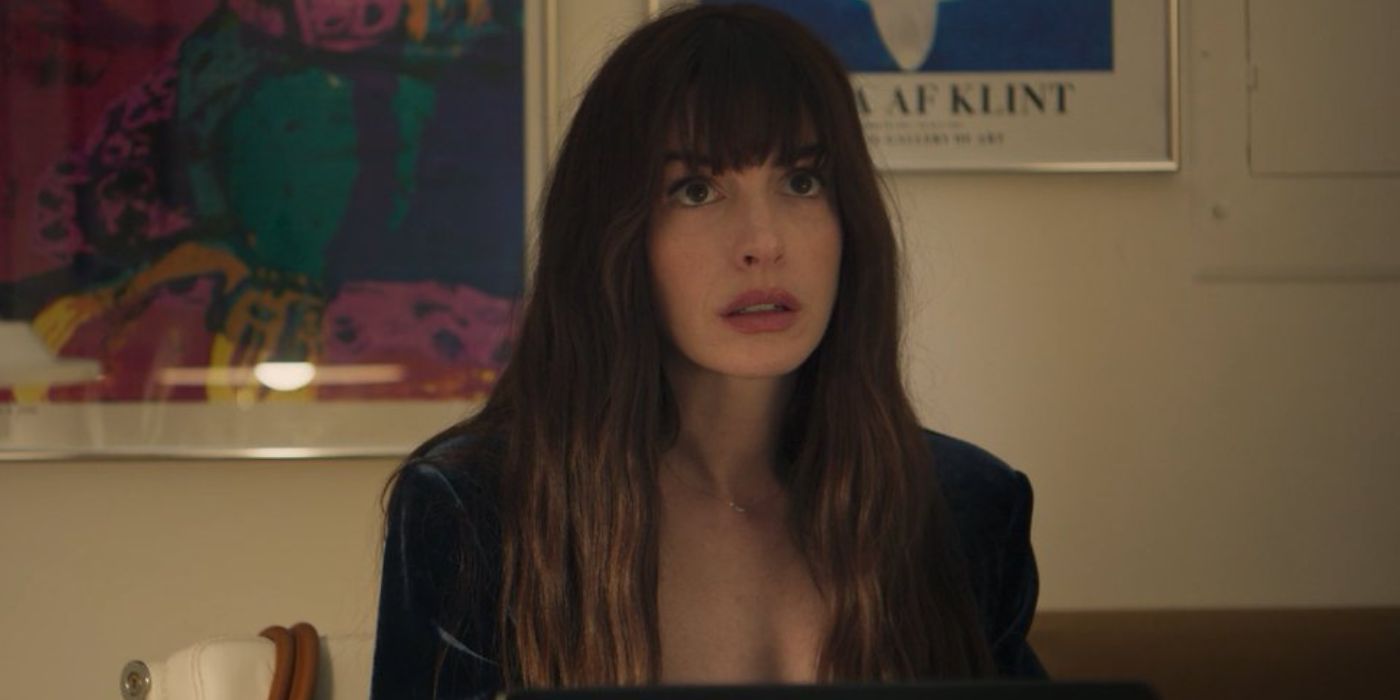 Anne Hathaway sitting in front of her computer wearing a dark blue blazer in 'The Idea of You'