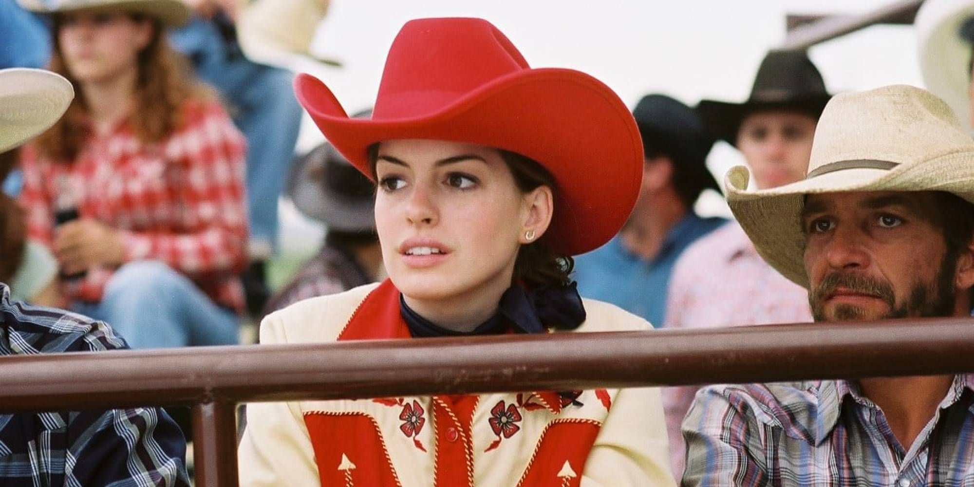 Anne Hathaway sitting with a red cowboy hat on in The Brokeback Mountain.