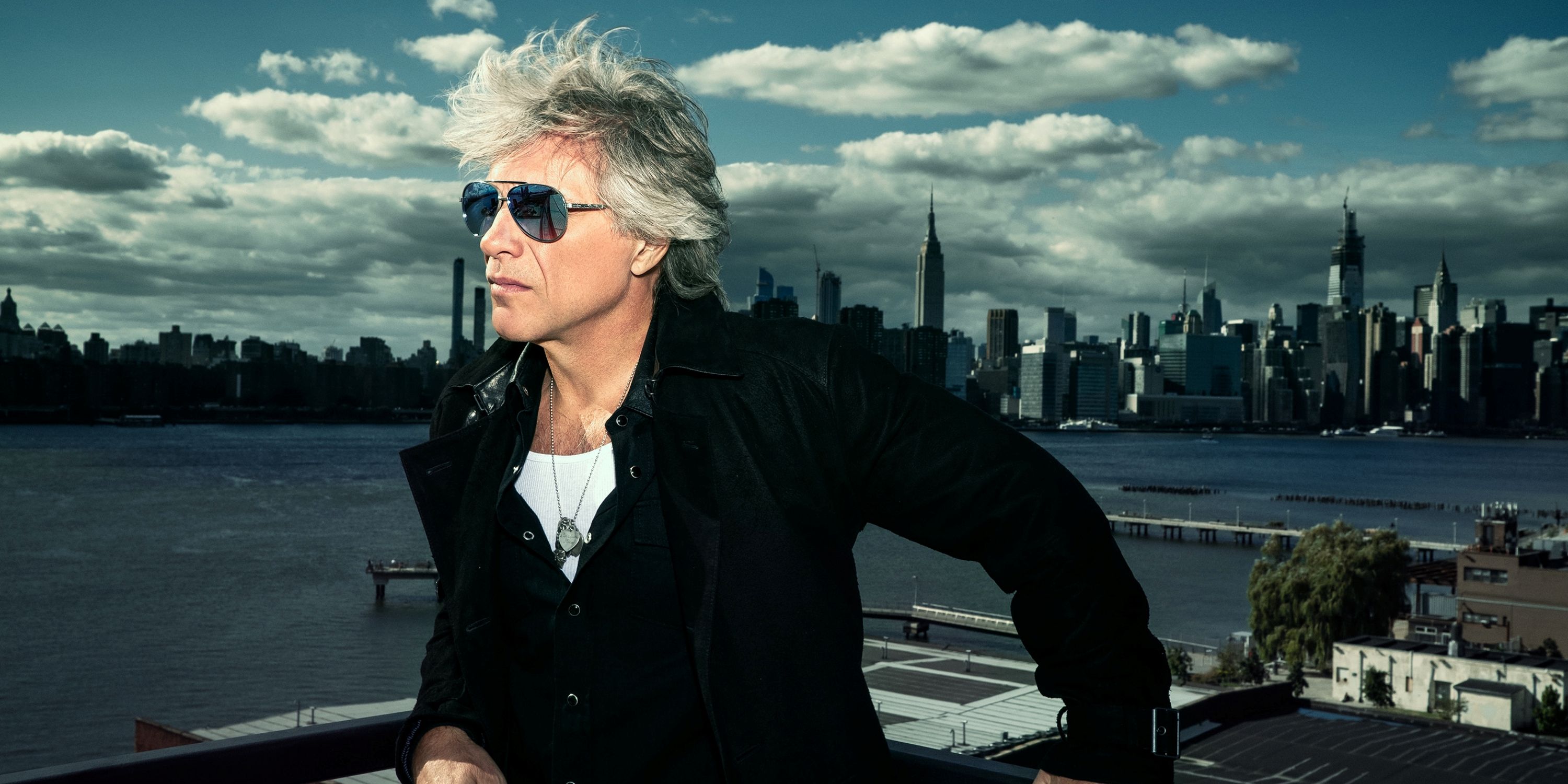 Approved headshot of Jon Bon Jovi in profile on a balcony with a body of water behind him 