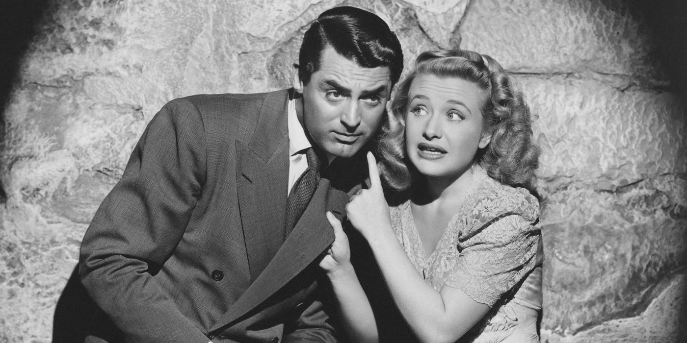 Mortimer Brewster (Cary Grant) and Elaine Harper (Priscilla Lane) take shelter together by a stone wall in 'Arsenic and Old Lace' (1944)