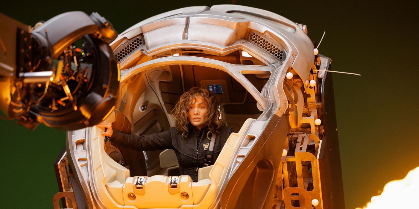 Jennifer Lopez riding in a robotic suit in front of a green screen in a behind-the-scenes photo from Atlas.