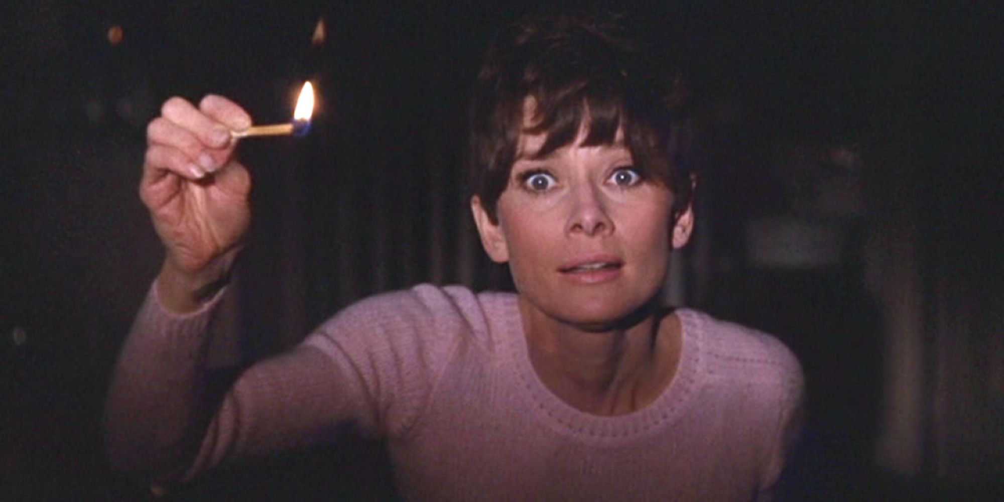 Audrey Hepburn holding up a lit match in a dark room in Wait Until Dark (1967)