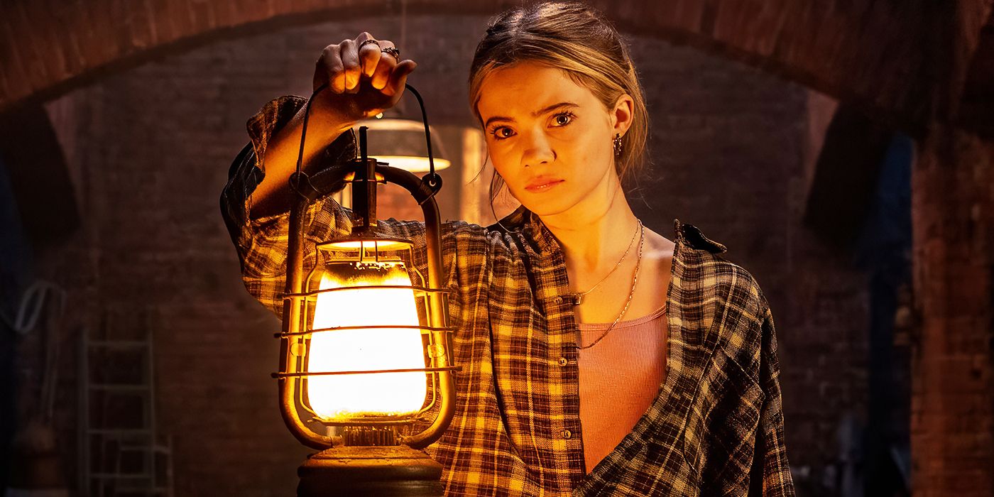 Freya Allan as Iris Lark holding a lantern in Baghead. 