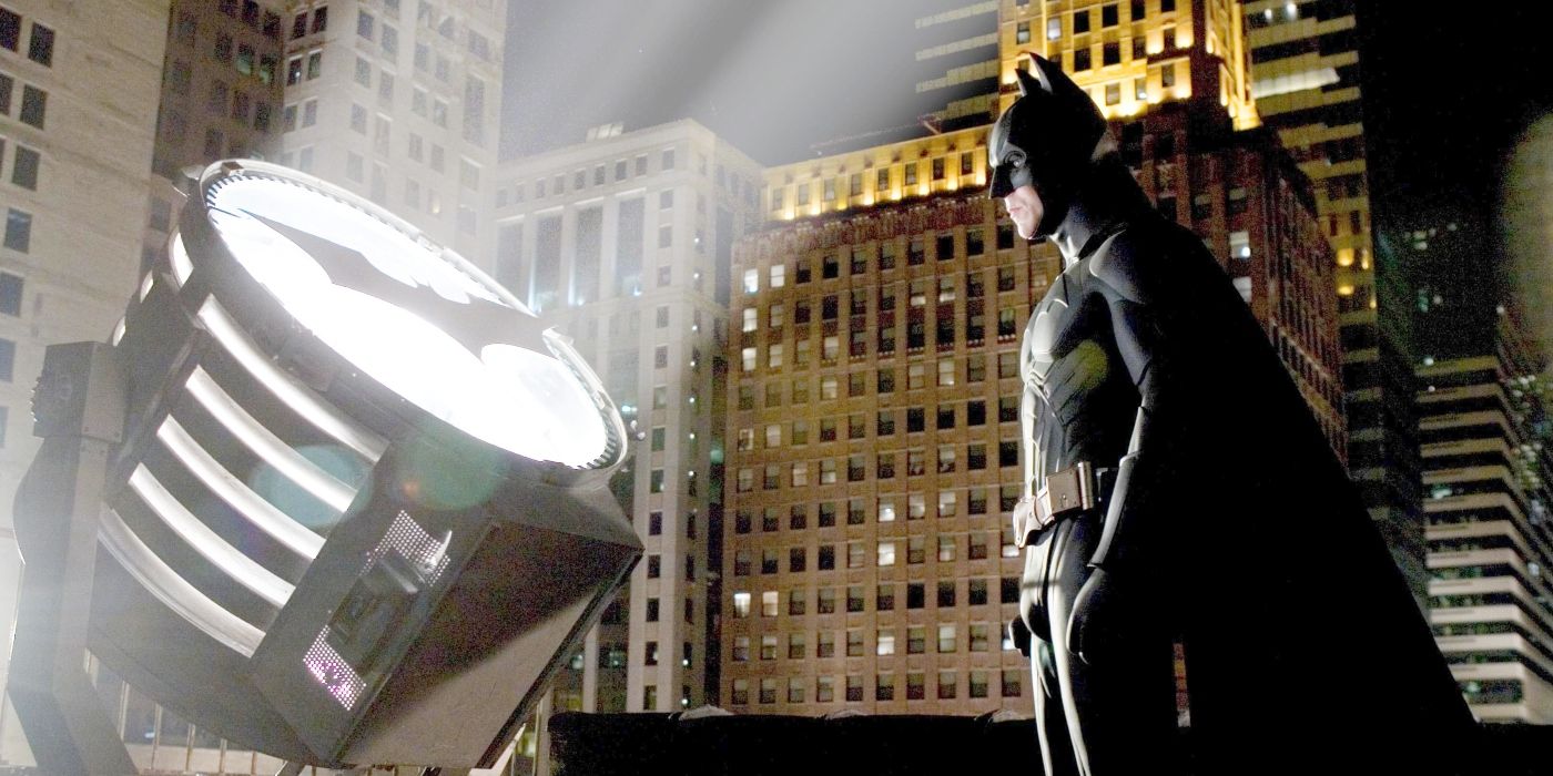 Batman standing before the Bat-Signal at night in Batman Begins 