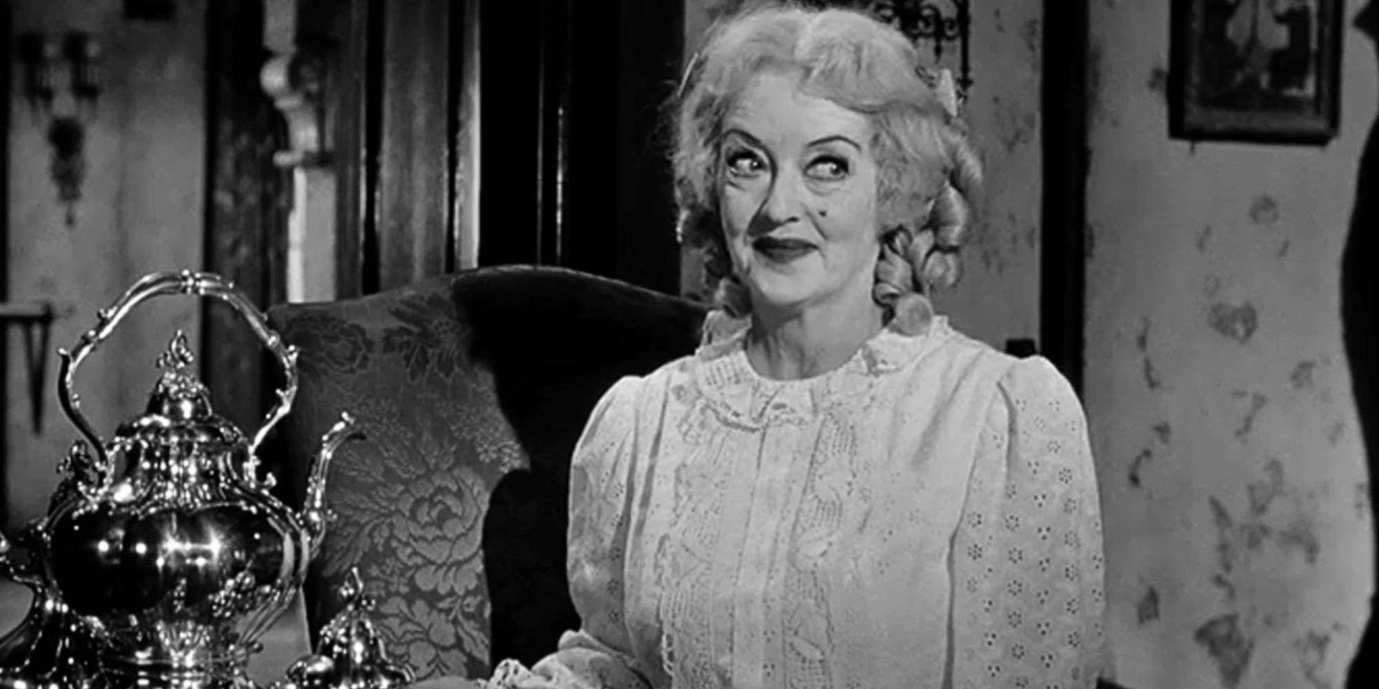 Baby Jane Hudson sitting and smiling mischievously in What Ever Happened to Baby Jane? (1962)