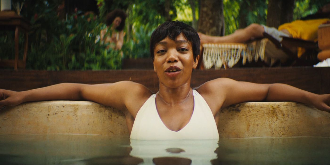 Naomi Ackie wearing a white bathing suit, and spreading out her arms, while in a hot-tub in Blink Twice.