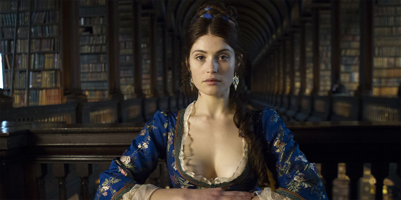Gemma Arterton as Clara in a historical dress sitting in a library from Byzantium