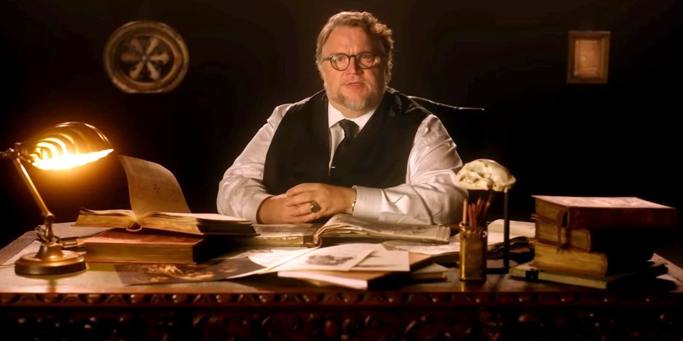 Guillermo del Toro sits at a desk filled with books and papers, talking to the camera in Cabinet of Curiosities.