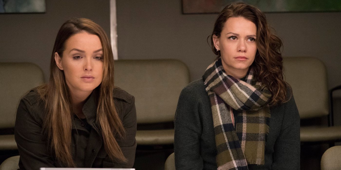 Camilla Luddington looking down as she sits next to Bethany Joy Lenz in the scene of 