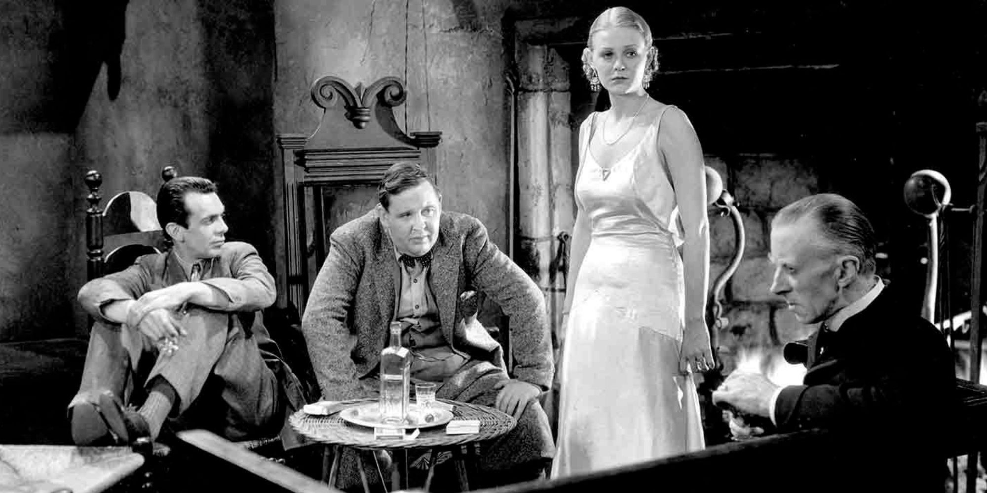 Charles Laughton, Raymond Massey, Gloria Stuart and Ernest Thesiger gathered around a fireplace in The Old Dark House (1932)