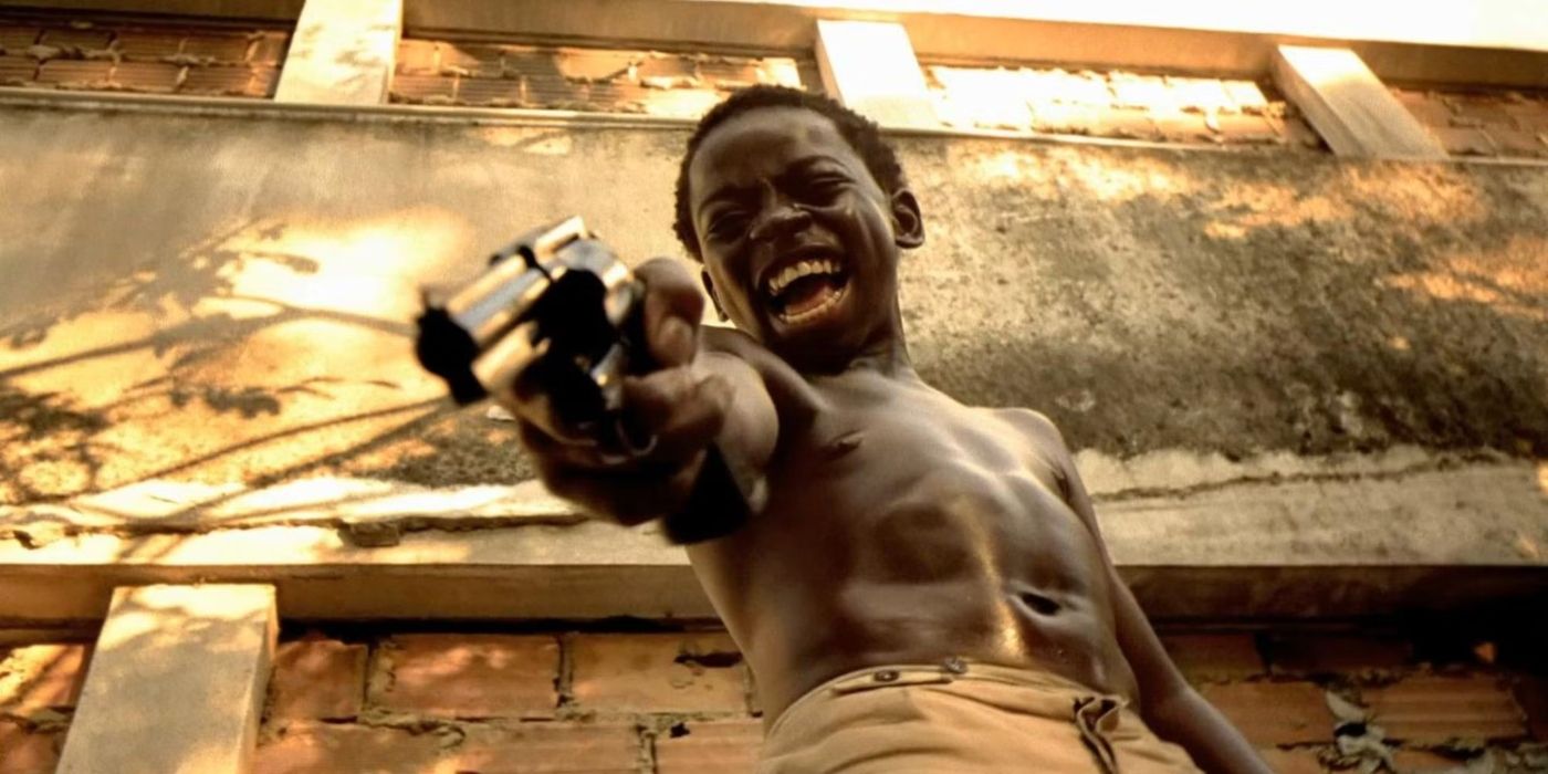 A young boy aiming a gun down at someone off-camera and screaming in rage in City of God