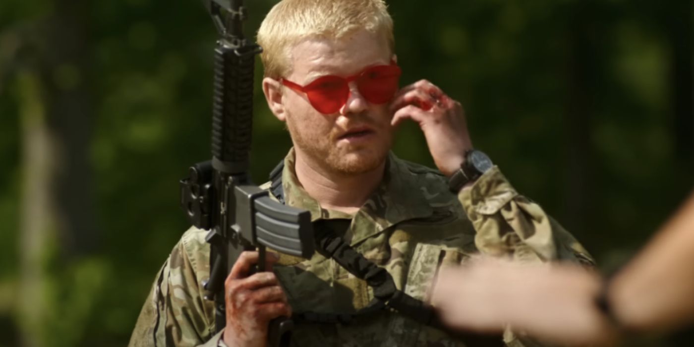 Jesse Plemons holds a rifle over his shoulder in Civil War. He is wearing red-tinted sunglasses and has blood on his hands.