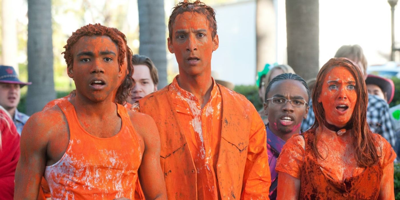 Troy (Donald Glover), Abed (Danny Pudi), and Annie (Alison Brie), covered in orange paint and looking sad in Community