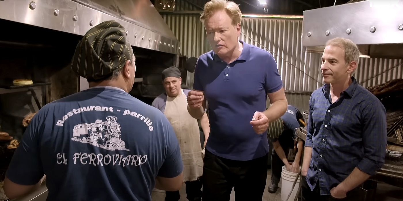 Conan O'Brien talks to Argentinian cooks in a kitchen in Buenos Aires with his associate producer Jordan Schlansky beside him in a scene from Conan O'Brien Must Go.