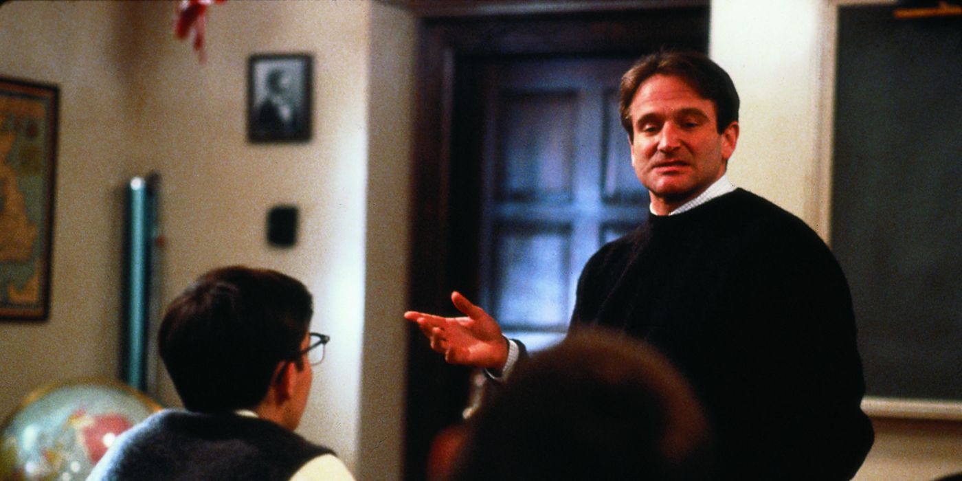John Keating (Robin Williams) speaking at the front of the classroom with this raised right hand in Dead Poets Society